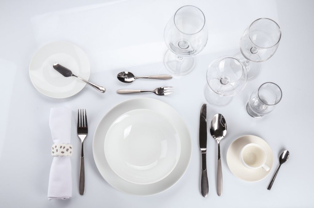 pratos, talheres e taças posicionados na mesa
